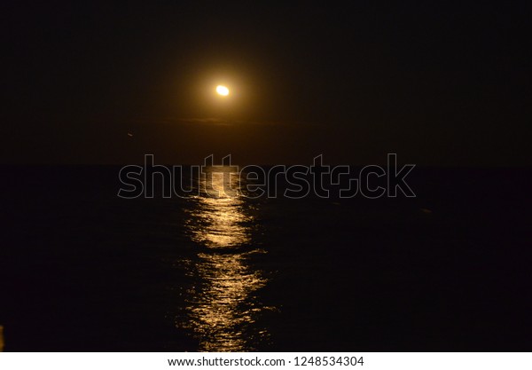 The moon reflects in\
the sea at night