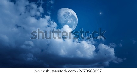 The moon rises from fluffy clouds. The full moon shines brightly in the dark blue sky. Quiet and serene night sky.