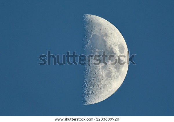 The moon showing against blue sky, detailed shot\
taken at 1600mm focal\
length