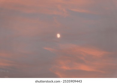 A moon at sunset with pink clouds