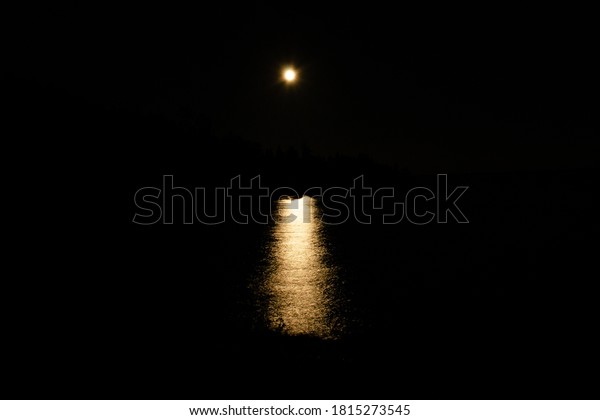 Moon trail at night it calm water of Ladoga lake\
among rocks, horizontal\
photo