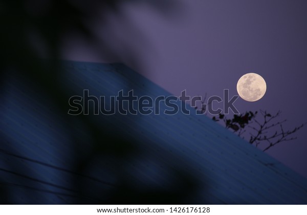 Moon at twilight with\
foreground objects, seen from Asia, silhouette foreground and\
pastel indigo sky