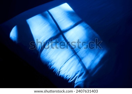 Moonlight coming through a window and reflecting on a bed. Blue.
