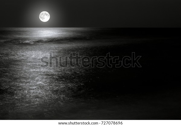 moonlight on the waves at night in the sea on long\
exposures. black and white\
photo.