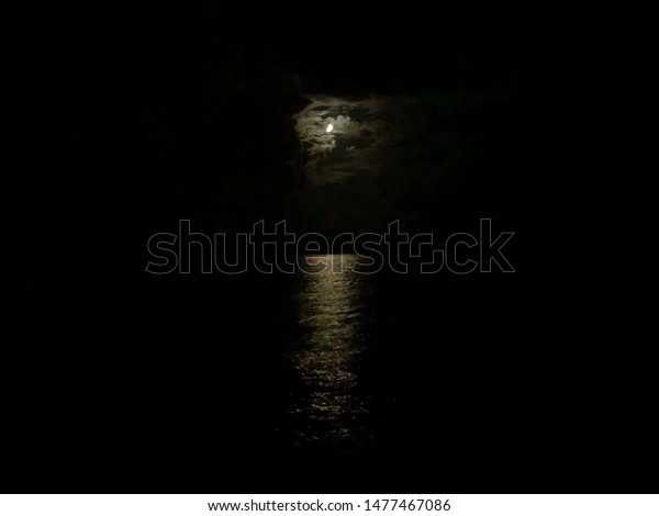 Moonlit path at sea at night. The\
dark sky, the moon is reflected in the water. Beautiful landscape\
in the night. Harmony with nature. Mysterious\
background.