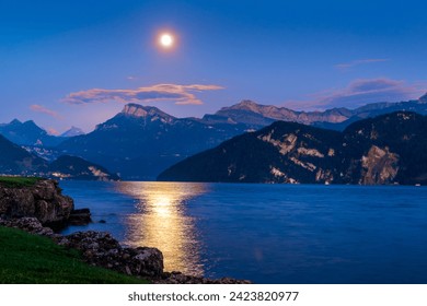 Moonlit scene at Lake Lucerne with clear sky and mountains in the background. Moon reflecting in the water creating a trail.  - Powered by Shutterstock