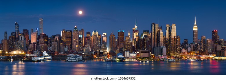 Moonrise over skyscrapers of Midtown Manhattan West at dusk from across the Hudson River. New York City, NY, USA