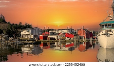 A moorage basin and fish processing plant at sunset at the mouth of the Columbia River at Ilwaco, Washington State for commercial fishing boats.
