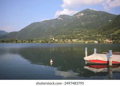 Moored boat on a mountain lake with its reflection casted on the water at sunset - Powered by Shutterstock