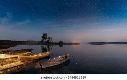 Moored Old Shabby Wooden Fishing Rowboats , Left Afloat On The Motionless Clear River Lake Water Next To Waterside. Amazing Glowing Stars Effects Above Lake. Night Starry Sky Soft Colors. - Powered by Shutterstock