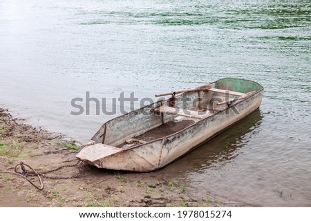 Moored rusty metal boat with oars . Fishing village 
