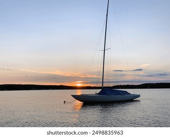 Moored sailboat in marina harbor at sunset. Sailboat shown against the backdrop of the Adirondack Mountains of New York and Vermont in Lake Champlain. - Powered by Shutterstock