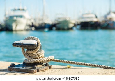 Mooring rope and bollard on sea water and yachts background