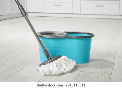 Mop and bucket on white parquet indoors. Cleaning floor - Powered by Shutterstock