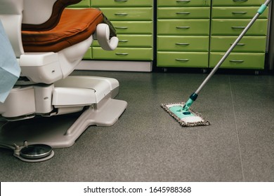 Mop And Dental Chair While Cleaning In A Green Office