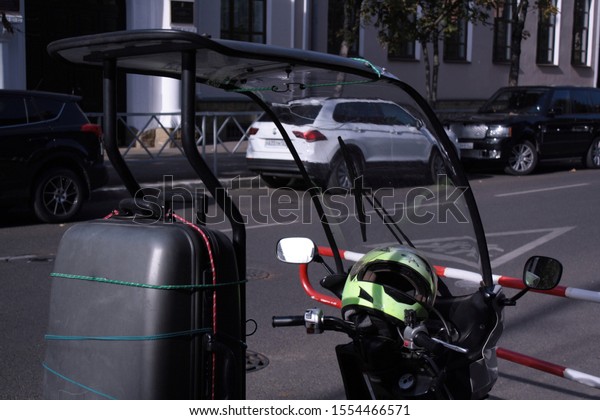 Moped on the street. Large luggage\
compartment. Mirror\
reflection