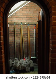 Mops And Brushes Hanging In A Cupboard