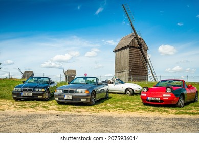 Moraczewo, Poland - August 09, 2021. Old convertible BMW e36 and Mazda MX5 Miata parked in front of wooden wind mills on road trip