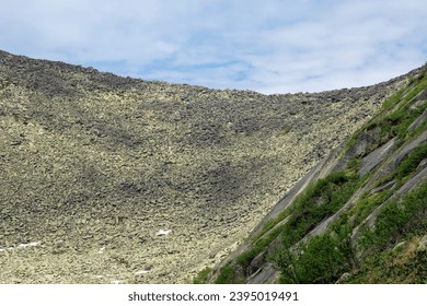 Moraine, crack rock. Steep mountain slope strewn with stones, a difficult climb up the kurumnik to the pass. - Shutterstock ID 2395019491