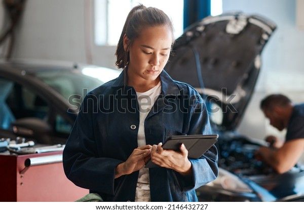 The more diverse your knowledge, the\
more customers you can help. Shot of a female mechanic using a\
digital tablet while working in an auto repair\
shop.