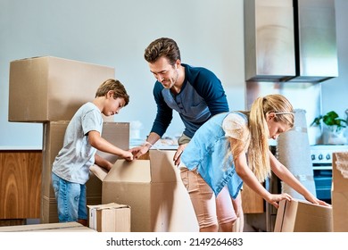 More Hands Make Less Work. Shot Of A Focused Young Family Working Together And Unpacking Boxes Out In Their New Home Inside During The Day.