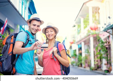 More Opportunities For Travel. Young Traveling Couple Holding Credit Card While Standing On The Asian Street Holding Backpacks.