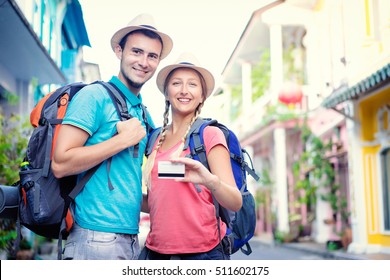 More Opportunities For Travel. Young Traveling Couple Holding Credit Card While Standing On The Asian Street Holding Backpacks.