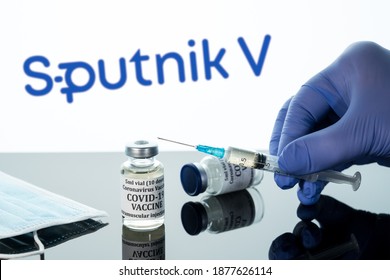 Morgantown, WV - 16 December 2020: Small bottle of coronavirus vaccine with syringe with background of Russian Sputnik V logo