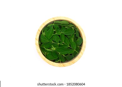 Moringa leaf on wooden bowl isolated on white background, top view. Moringa oleifera is both food and herbal medicine.