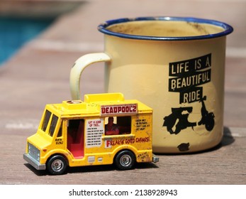 Morning activity concept with mini car toys. Unfocus old iron mug with text as a accsessories on a wooden table in the outdoors. 