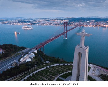 Morning aerial view from Almada of Sanctuary of Christ King and 25 de Abril Bridge against backdrop of lighted Lisbon, Portugal .. - Powered by Shutterstock