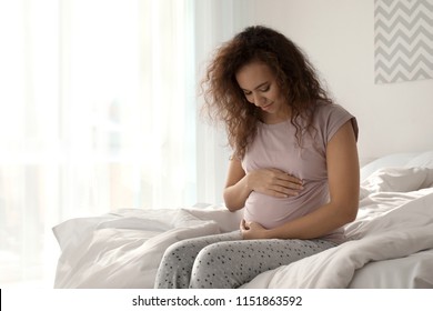 Morning of beautiful pregnant African-American woman in bedroom