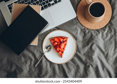 Morning bed with notebook, laptop, coffee cup and piece of strawberry cheesecake on the grey bed sheet. Cozy weekend morning at home. Work morning with dessert and coffee. - Powered by Shutterstock