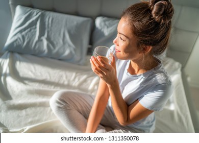 Morning Breakfast In Bed Happy Asian Woman Drinking Hot Coffee Mug Relaxing Sitting On Mattress. Weekend Relaxation Wellness.