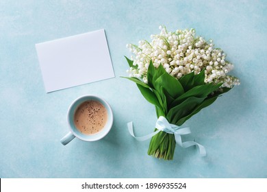 Morning breakfast from fresh coffee cup and spring bouquet of flowers lily of the valley with empty greeting card top view and flat lay.