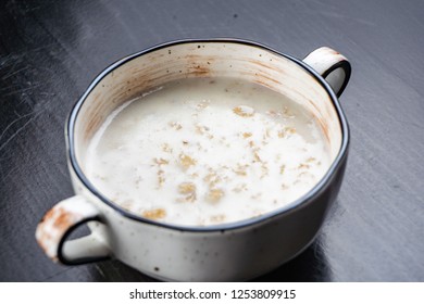 Morning Breakfast, oatmeal on milk with butter in white plate on dark background