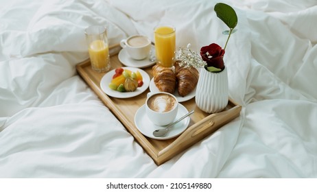 Morning Breakfast Tray. Close Up Shot Of A Delicious Looking Breakfast, Consisting Of Coffee, Orange Juice, Croissants And Fruits, Put On A Bed In A Fancy Hotel Suite.