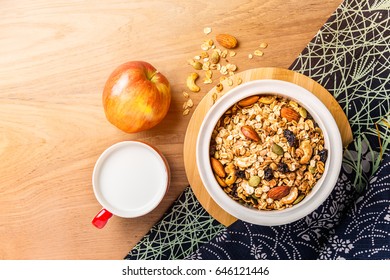 Morning Cereal In A Bowl With Full Apple And Cup Of Milk On Wood Table With Asian Style Napkin, Side Warm Morning Light, Room For Copy Space