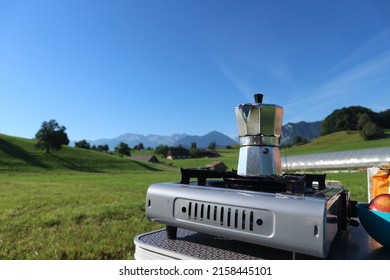 Morning coffee with Bialetti on gas stove in green meadow and blue sky in the Swiss alps
