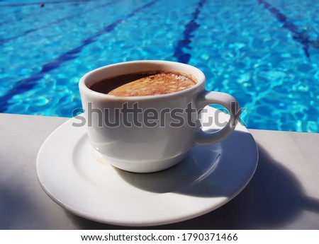 Morning coffee on the background of the blue swimming pool