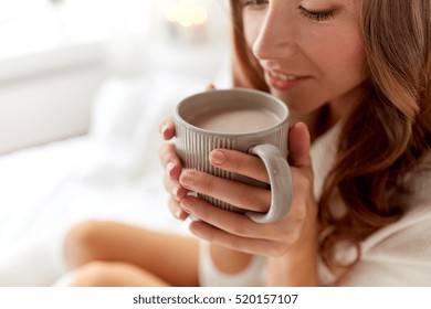 Morning, Coziness, Winter And People Concept - Close Up Of Happy Young Woman With Cup Of Coffee Or Cocoa Drink In Bed At Home