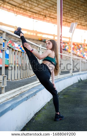Morning exercises on stadium. Young, sporty and slim woman making exercises