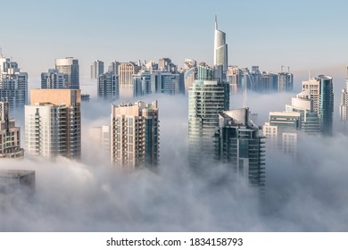 Morning fog hovering skyscrapers at sunrise. Building rooftops over the clouds in Dubai Marina
 - Powered by Shutterstock