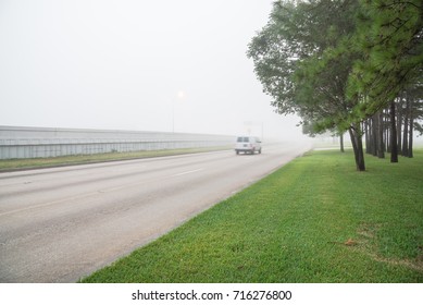 Morning foggy city frontage road, traffic sign and car motion in Humble, Texas, USA. Driving with caution in bad weather. Hazy transportation hazard. Severe weather theme concept background. Rear view - Shutterstock ID 716276800