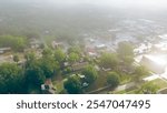 Morning foggy over West Gentry Avenue in downtown Checotah, small town in McIntosh County, Oklahoma, mix of commercial buildings, churches, schools, residential neighborhood, lush green, aerial. USA