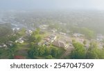 Morning foggy over West Gentry Avenue in downtown Checotah, small town in McIntosh County, Oklahoma, mix of commercial buildings, churches, schools, residential neighborhood, lush green, aerial. USA