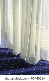 Morning At A Glance: Bottom Of Sheer Drapes Almost Touching Carpet By Glass Door To Hotel Balcony