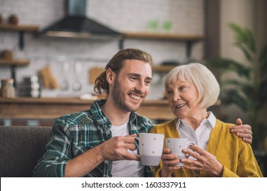 In the morning. Grey-haired elderly woman having morning coffee with son