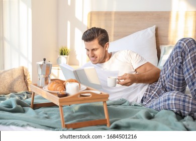 Morning Of Handsome Young Man Reading Book During Breakfast In Bed