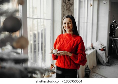 Morning of a happy woman in red sweater enjoying coffee in a winter holiday atmoshpere